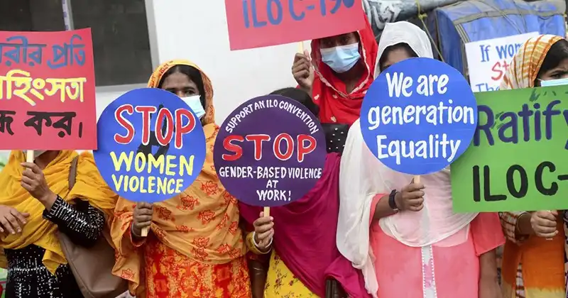 زنان معترض با لباسی سنتی که پلاکاردهایی با شعار توقف خشونت علیه زنان و حمایت از کنوانسیون سازمان بین‌المللی کار درباره خشونت جنسیتی در محیط کار در دست دارند.