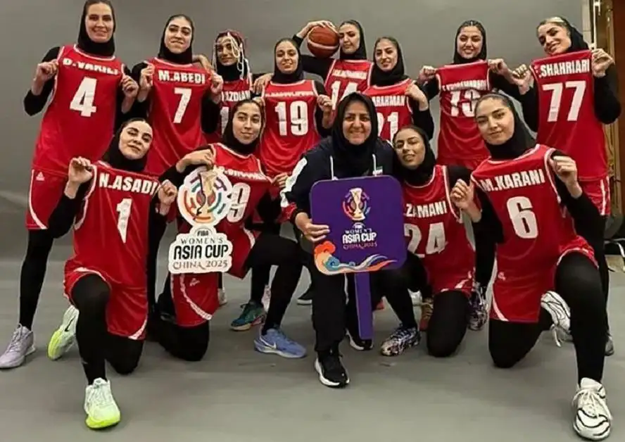 Team photo of female basketball players wearing red jerseys and hijabs posing together, several holding up numbered jerseys and a sign reading "Women's Asia Cup China 2025."